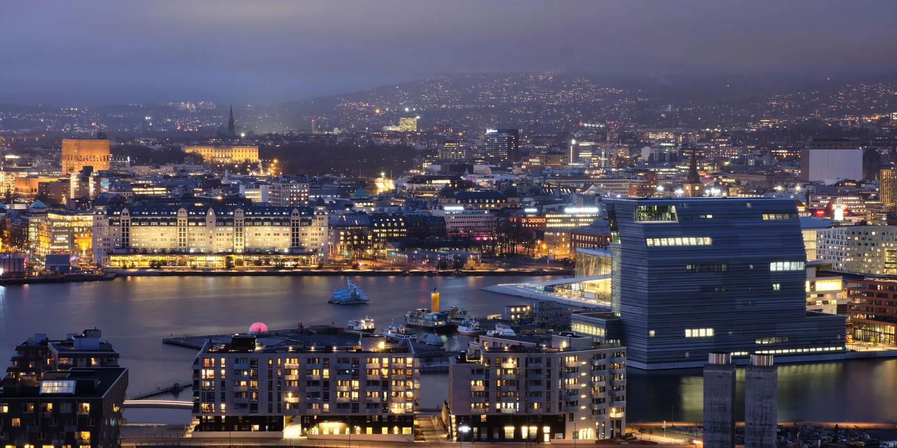 The Munch Museum tower beside the lit Oslo waterfront at dusk